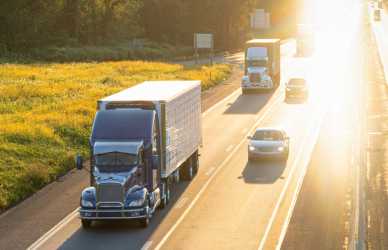 four lane highway with cars and semi trucks and bright sun