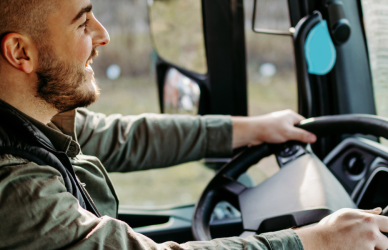 truck driver behind the wheel of semi truck in cab driving on road