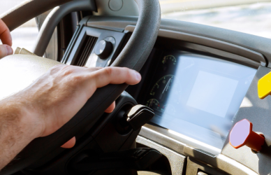 man's hands on the wheel of a semi truck from an in-cab perspective