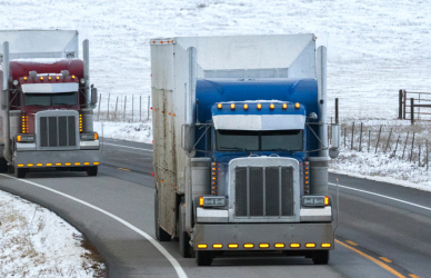 two semi trucks on snowy, curvy road
