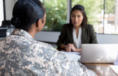 veteran woman in uniform sitting across from woman in suit with laptop