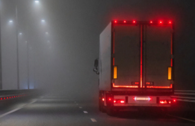 semi truck driving at night with brake lights lit up