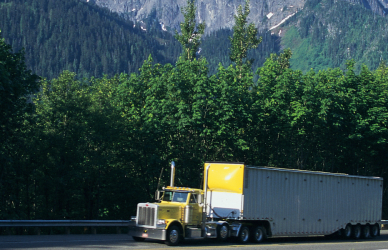 yellow semi truck navigating high elevation mountain road with forest and mountains in background, elevation and truck performance