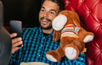 man with teddy bear holding phone in sleeper area of semi truck stopped at truck stop resting trucker trucker downtime