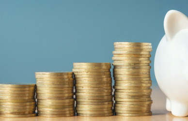 stacked coins next to piggy bank on blue background, U.S. Department of Transportation's PHMSA has proposed a rule to save businesses and consumers nearly $100 million annually by modernizing hazardous material transport regulations