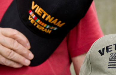 old man holding Vietnam veteran hat with veteran hat sitting in lap. OOIDA’s Truckers For Troops donates $10,000 to the Veterans Community Project in Sioux Falls, supporting their mission to end veteran homelessness