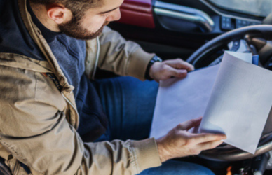 trucker in truck cab with paperwork