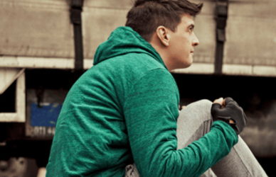 young man doing sitting on yoga mat next to semi truck