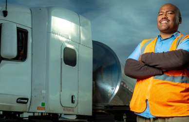 black man standing in front of white semi truck with folded arms