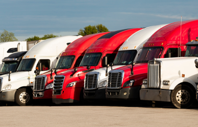 Variety of semi trucks parked in a row in a parking lot designed for truck parking