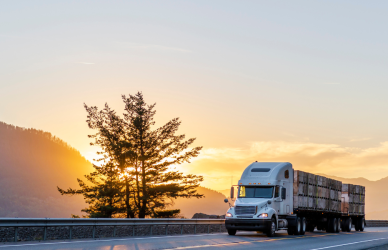 semi truck on road at sunset with mountain in background