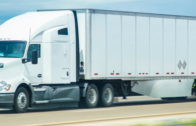 white semi truck with white trailer dry van semi truck on road with mountains in background