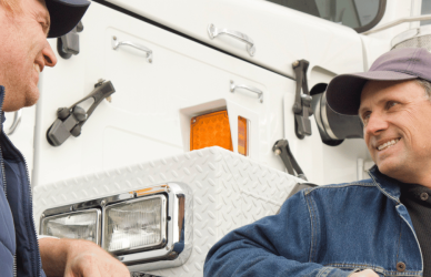 two men standing in front of a semi truck