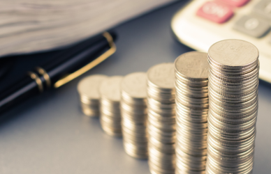 calculator, pen, papers, and growing stacks of coins