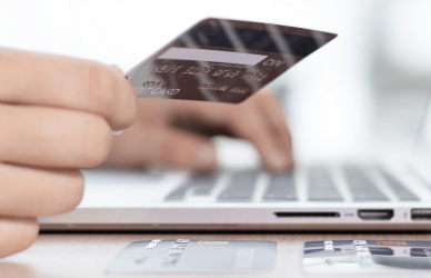 hand holding credit card over laptop keyboard for online shopping