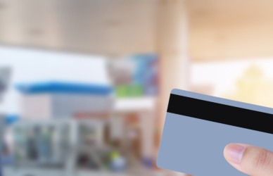credit card in foreground and fuel pumps in background