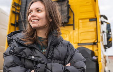 young woman standing in front of semi truck