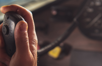 Hand holding cb radio inside cab of semi truck