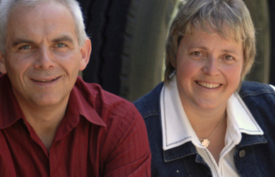 older couple sitting in front of semi truck tires