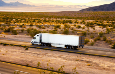 semi truck on open highway with mountains in the background