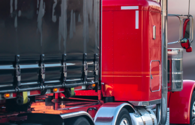 red semi truck with black trailer on road