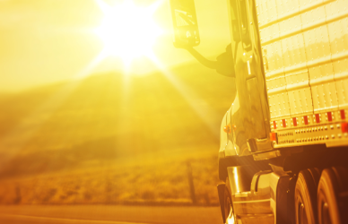 semi truck driving into bright sunset