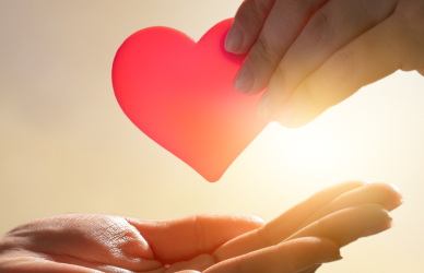 hands passing heart in sunshine