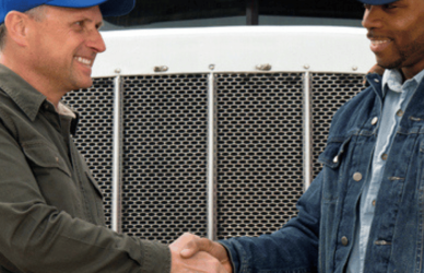 two men shaking hands in front of semi truck