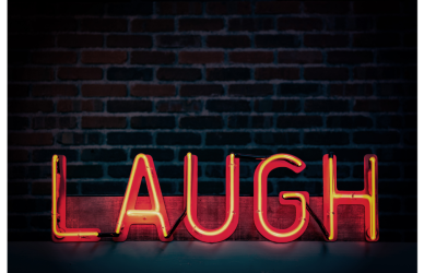 red neon laugh sign with a black brick background