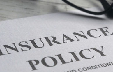 Insurance policy on desk next to calculator and glasses