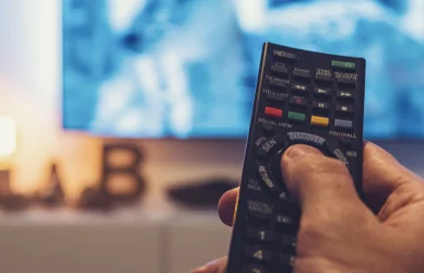 man holding remote towards television set