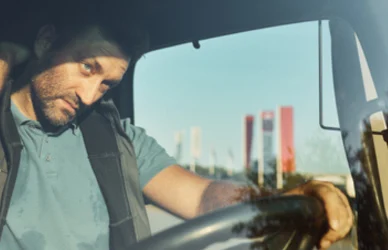 man driving a semi truck rubbing his neck