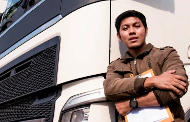 instructor with clipboard stands next to line of parked semi trucks