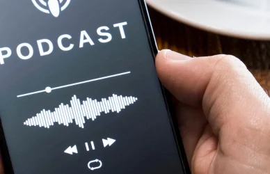 Man holding phone with screen displaying podcast playing info