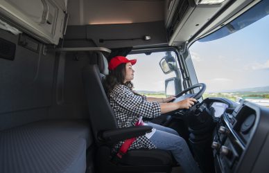 Happy female truck driver driving on a sunny day.Trucker occupation.