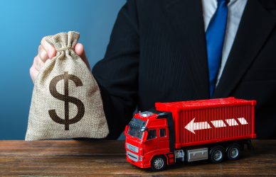 Businessman with dollar money bag and truck. High income of the transport business and the transport of goods. Good salaries for drivers. Rising prices, global containers shortage crisis. Logistics