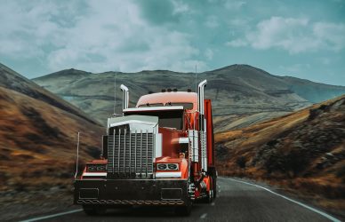 A red truck runs on a mountain road.