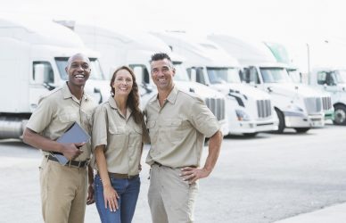Three workers in front of semi-trucks